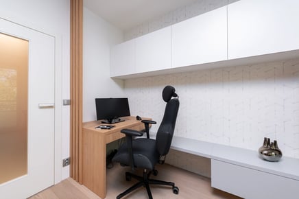 Světlý moderní interiér pracovny s psacím stolem a židlí.